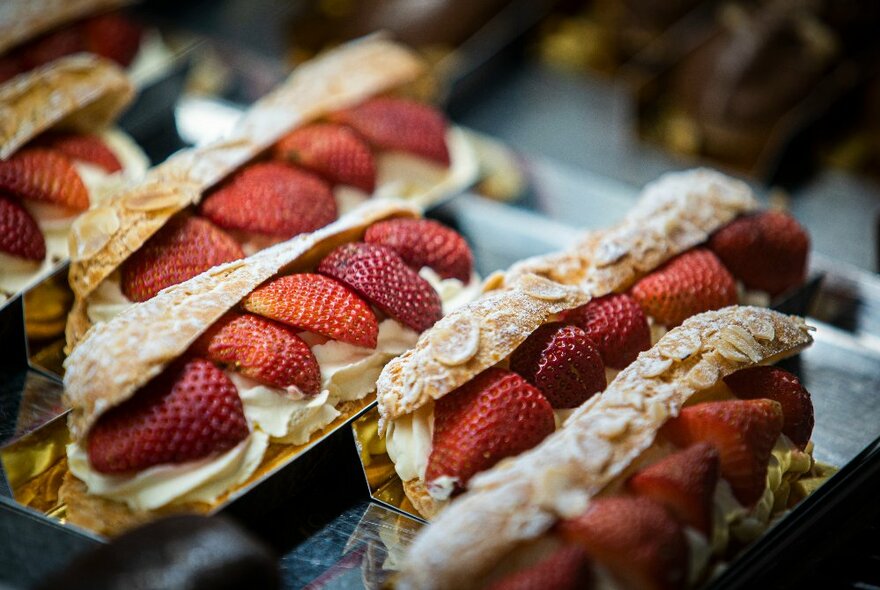 Trays of pastries filled with strawberries and cream.