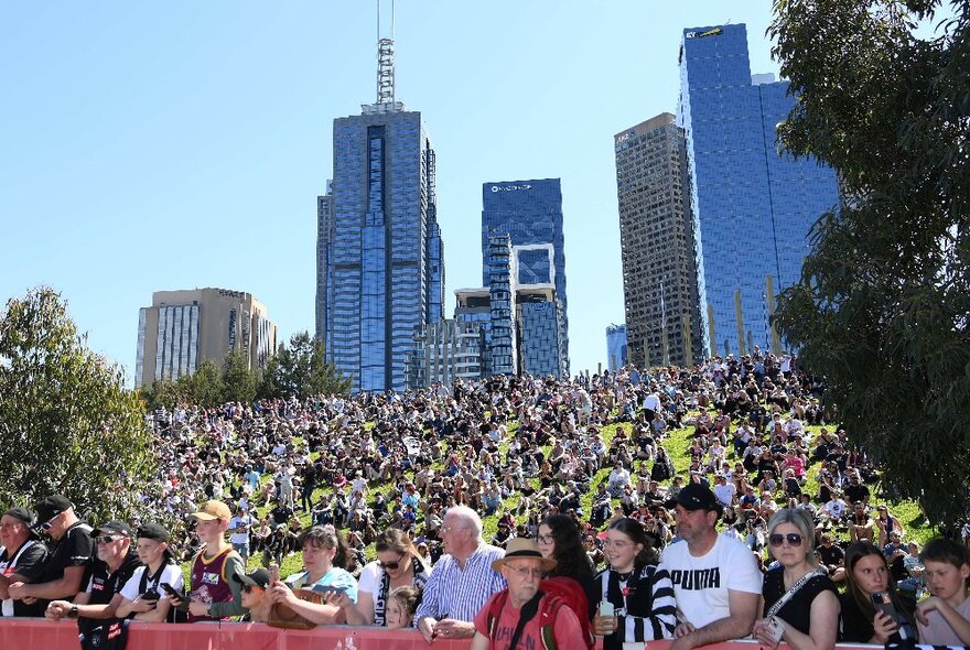 A huge crowd of people with the Melbourne city skyline behind. 