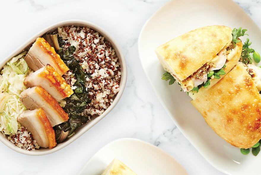 A table with a pork and rice bowl and a chicken and rocket focaccia