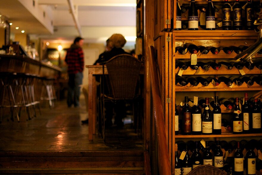 A warm glow looking through Il Solito Posto, a full wine rack on the right.