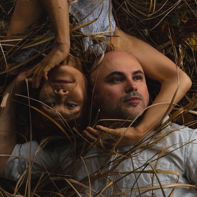 Dancers lying in grass, each framing each other's head with their arms.