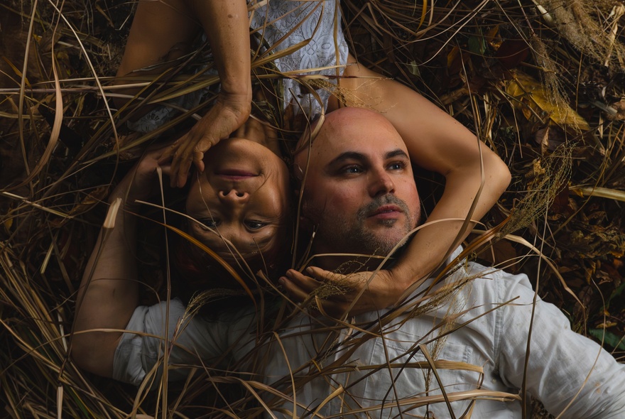 Dancers lying in grass, each framing each other's head with their arms.