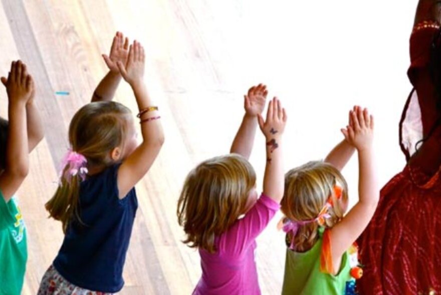 Children dancing in a line with arms raised.