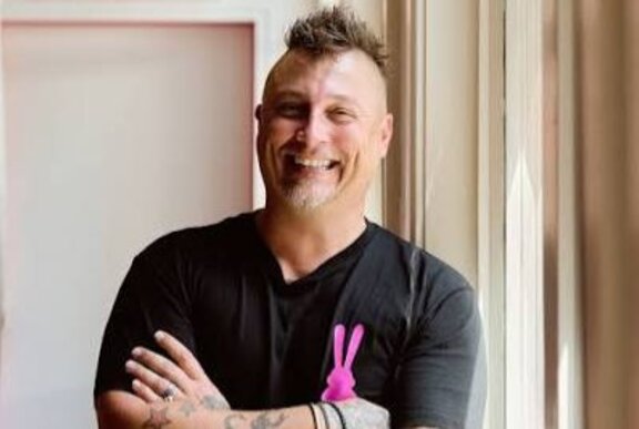Smiling chef with arms folded, with mohican haircut.