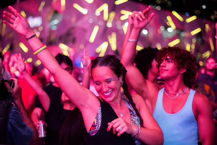 Crowds of people at Fed Square enjoying themselves and dancing at a music event.
