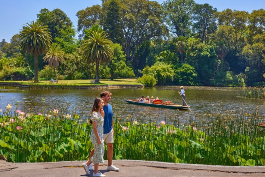 Two people walking in front of a river. Punter's are floating down the river.