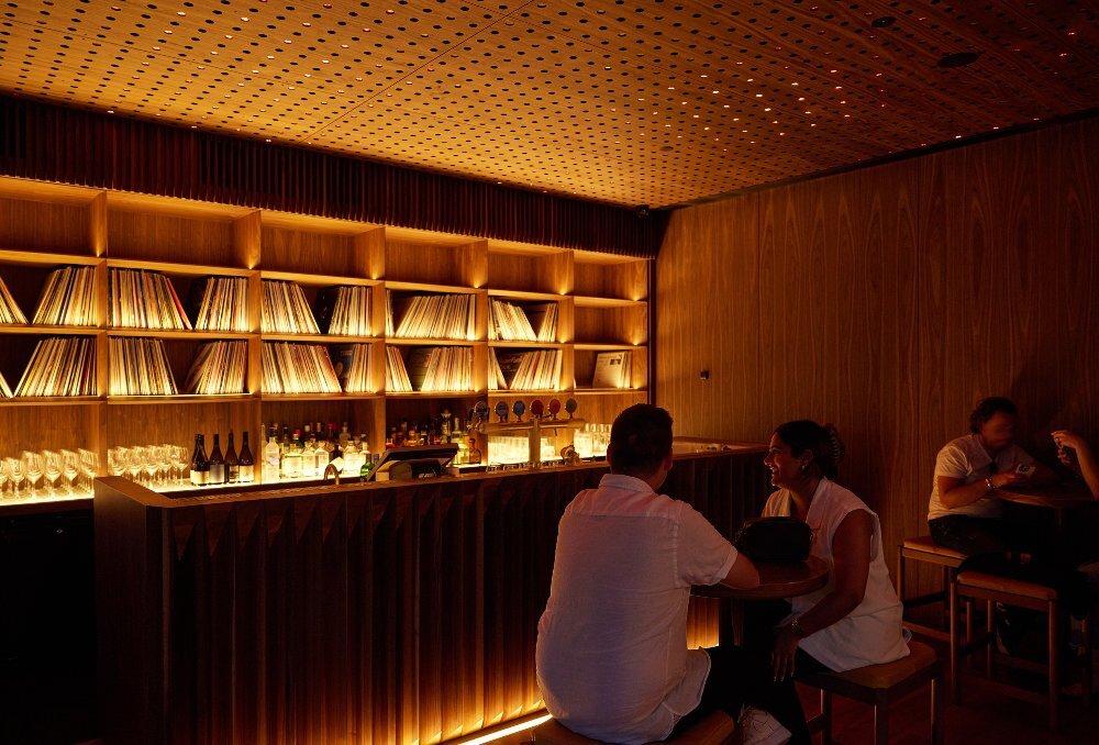 Two friends are in a dimly-lit record bar