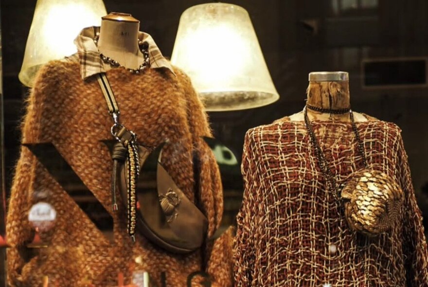 Store mannequins displaying layered winter fashion and handbags.