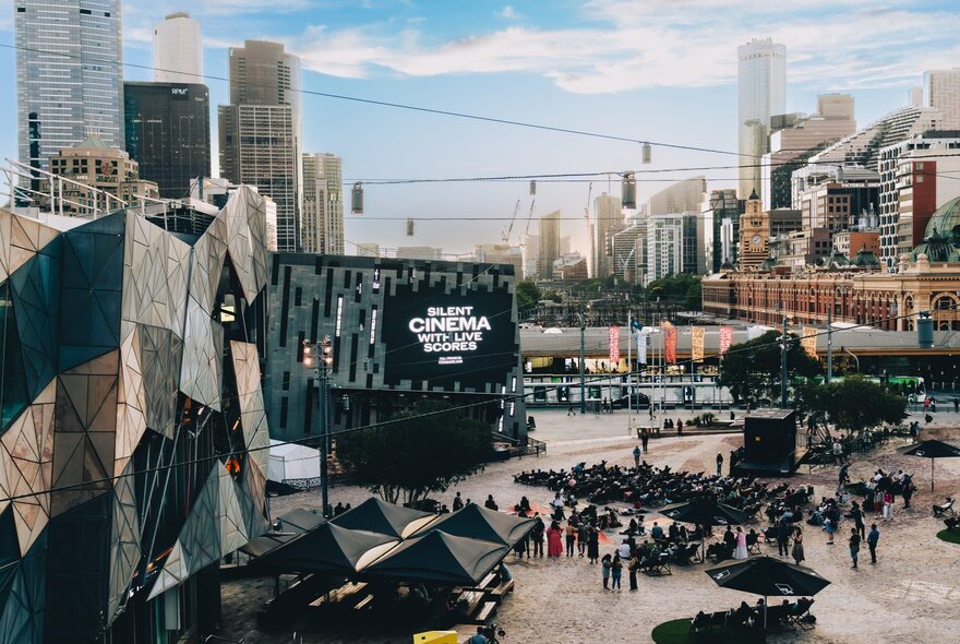 Melbourne's Fed Square set up with bean bag chairs in front of a large cinema screen for an open air film screening.