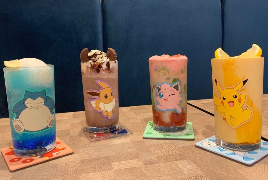 Four beverages served in tall glasses decorated with colourful Pokemon characters.
