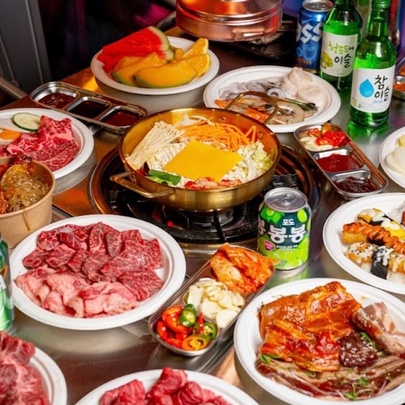 A Korean barbecue buffet featuring a hot pot in the centre and plates of ingredients.