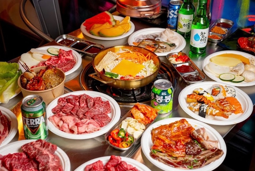 A Korean barbecue buffet featuring a hot pot in the centre and plates of ingredients.