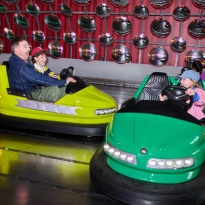 A dad and kids driving dodgem cars.