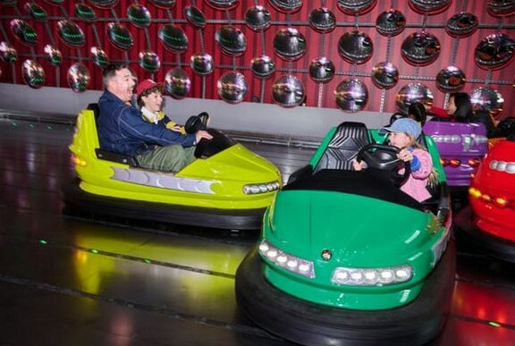 A dad and kids driving dodgem cars.