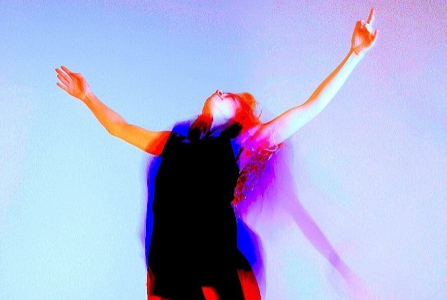 Blurred figure dancing with head back and arms outstretched.