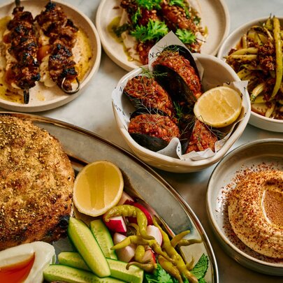 Plates of Middle Eastern food as part of a mezze lunch spread, on a restaurant dining table.