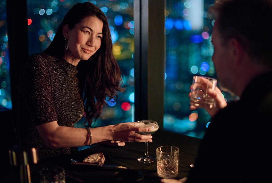 Two people enjoying a drink at a table in a restaurant, dim lighting.