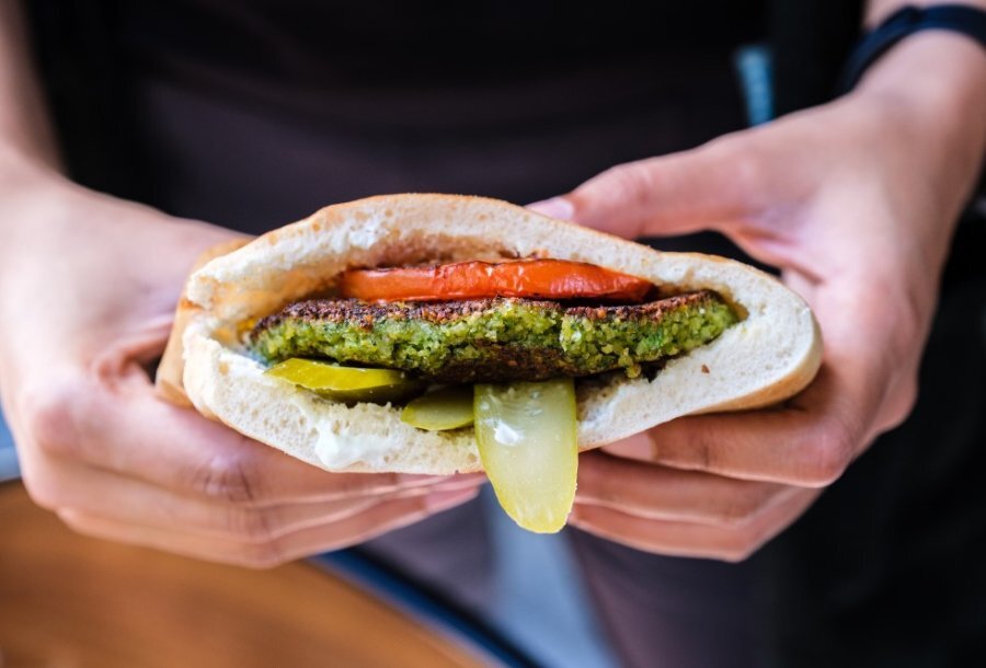 A pita filled with tomato, pickles and a falafel burger. 