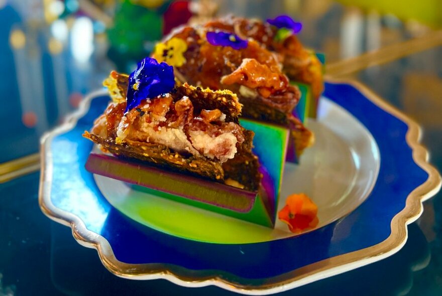 Pieces of cake with violets on a bright purple plate.