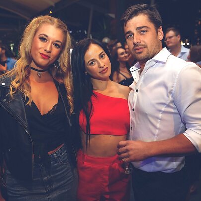 A group of three people posing for a photograph in a nightclub.