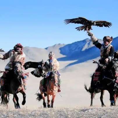 Mongolian horsemen in the desert with hunting birds.