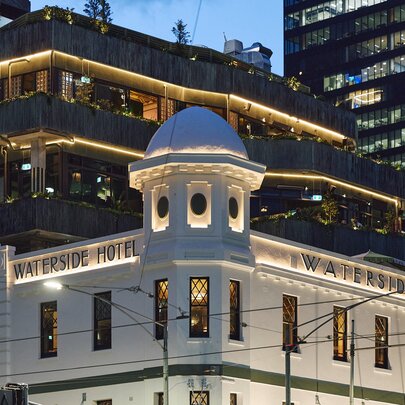 The external facade of the Waterside Hotel, with a vertical garden on the building behind it, seen from the corner.