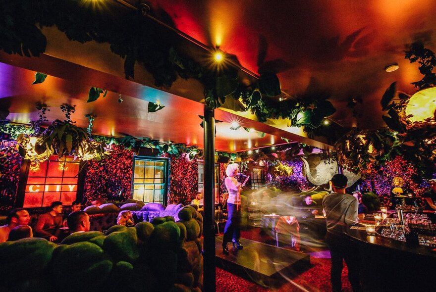 Neon-lit bar with mirror balls, lighting, low couches and tables.