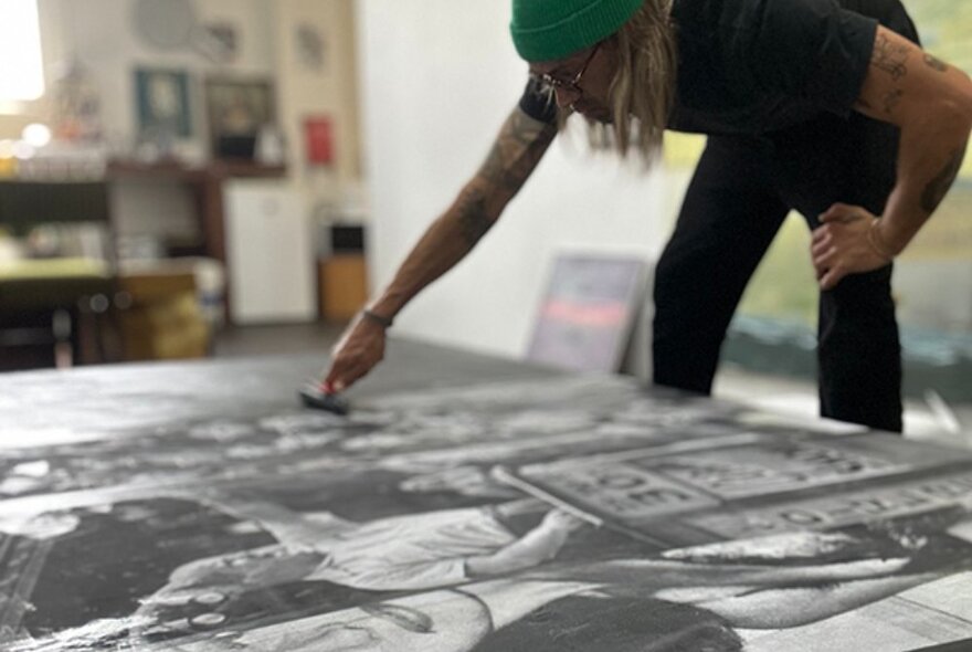 Artist creating a large-scale artwork on the floor.