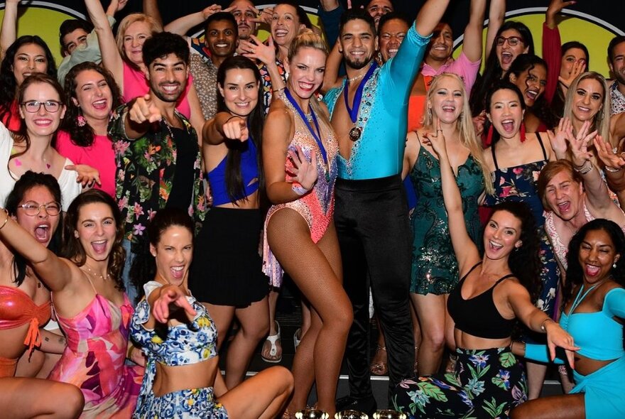 Seated and standing dancers waving their arms, wearing leotards and sarongs.
