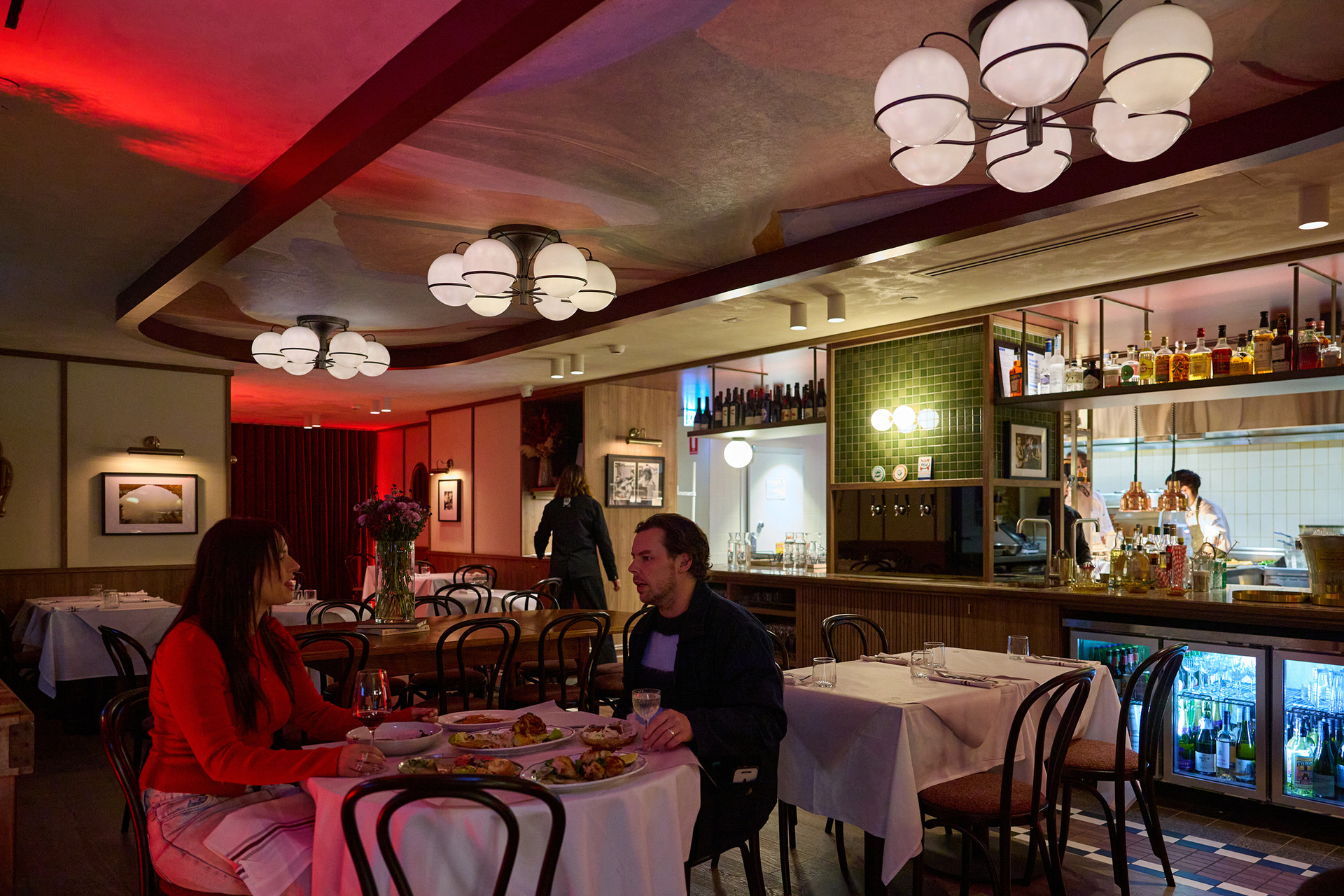 Two people are eating dinner inside a dimly lit restaurant