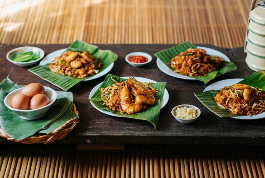 Prawns, eggs and other dishes on a wooden bench on bamboo.