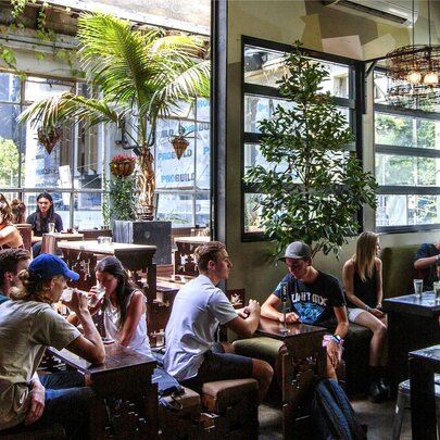 Interior of bar showing with people seated at small tables and windows overlooking the street.