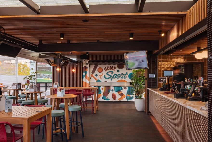 A rooftop bar with a tv and mural.