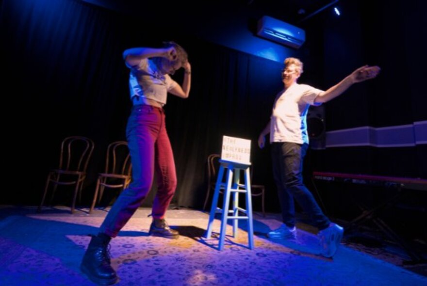 A live performance on a stage, with two actors improvising in front of an audience. 