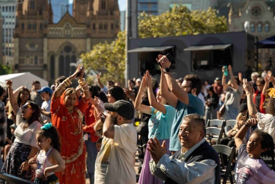 A crowd clapping and celebrating as they watch a performance.