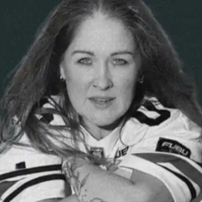 Woman with long dark hair, seated looking forward with arms crossed.