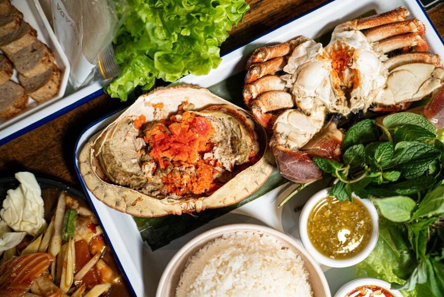 Thai dishes on a tray including rice, seafood and garnishes.