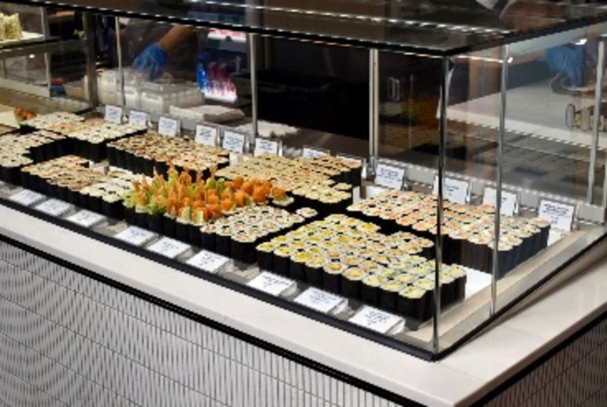 The food display counter at Maki Roll with sushi and maki rolls on trays behind glass.