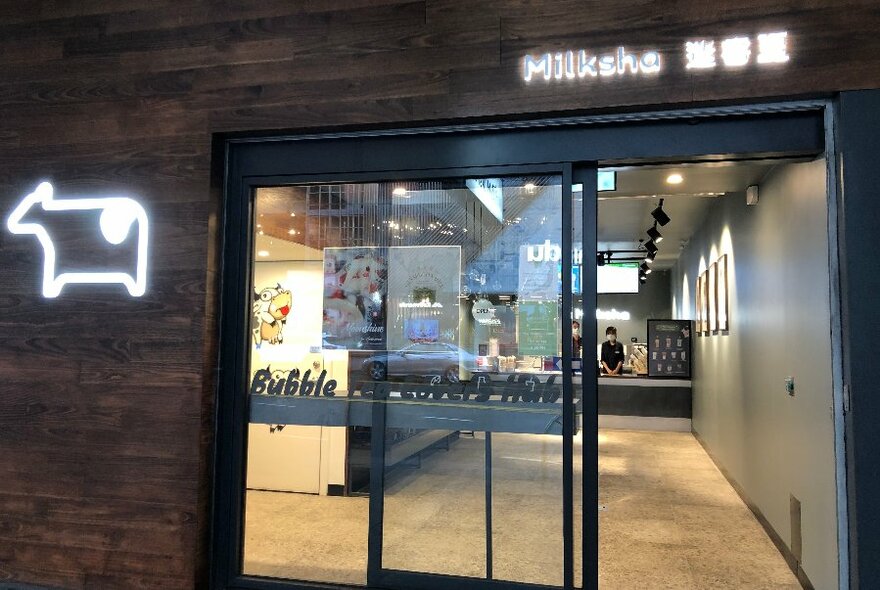 Entrance to a bubble tea store with a neon cow sign. 