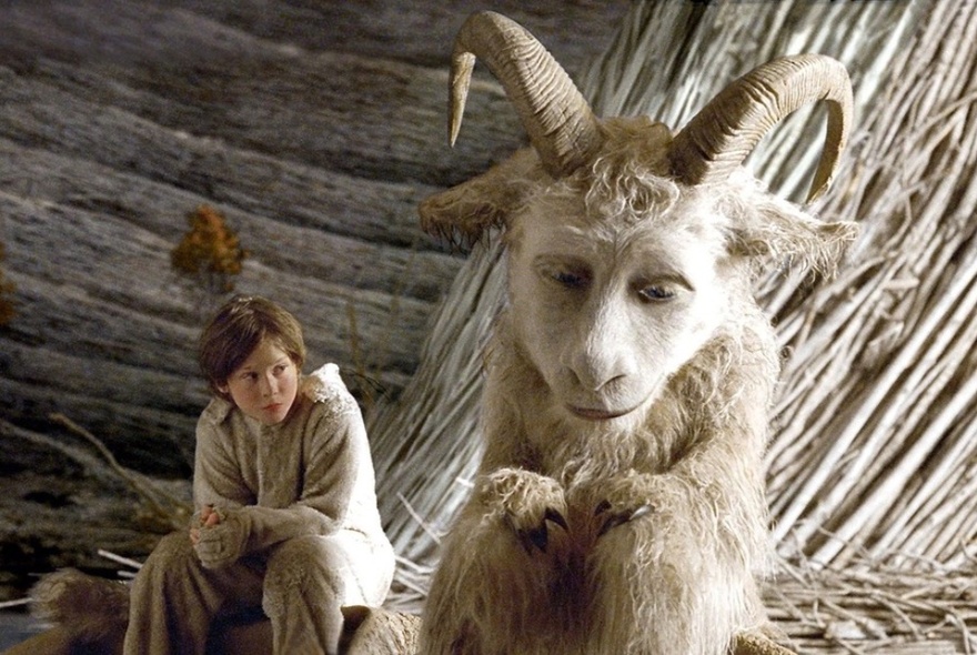 A still image from the movie Where the Wild Things Are showing Max sitting with large goat-like monster. 