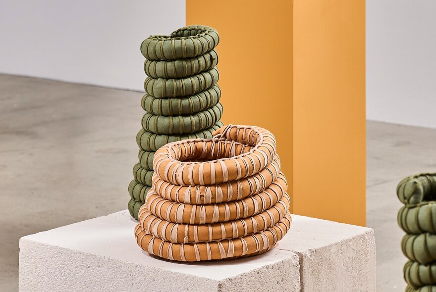Woven objects on a stone plinth display in the white gallery space at Craft Victoria.