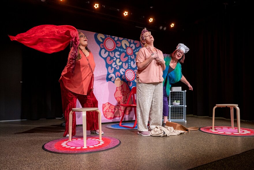 Three actors on a stage performing a play with props.