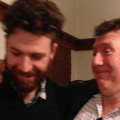 Two men laughing, with arms on each other's shoulders.