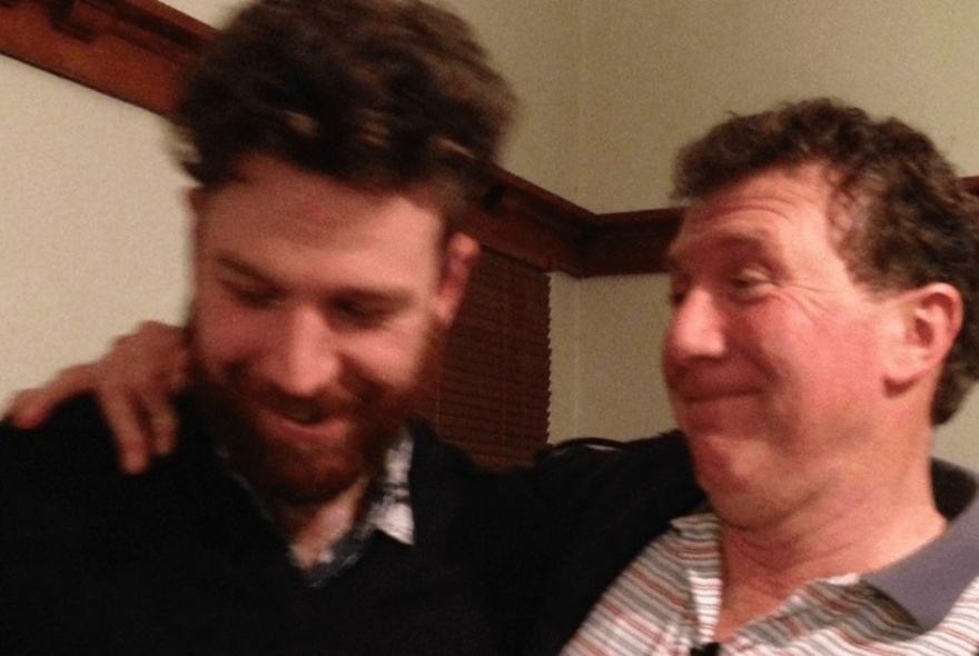 Two men laughing, with arms on each other's shoulders.