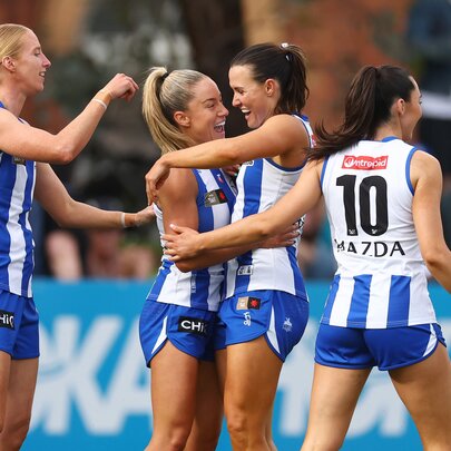 Players from the North Melbourne Kangaroos celebrating a goal during an AFLW match.