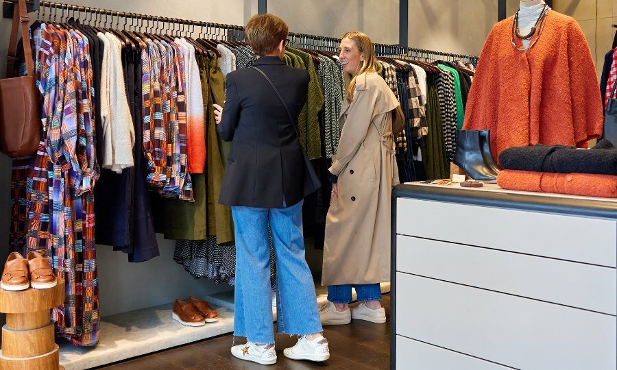 A mother and daughter shopping for winter clothing in a boutique. 