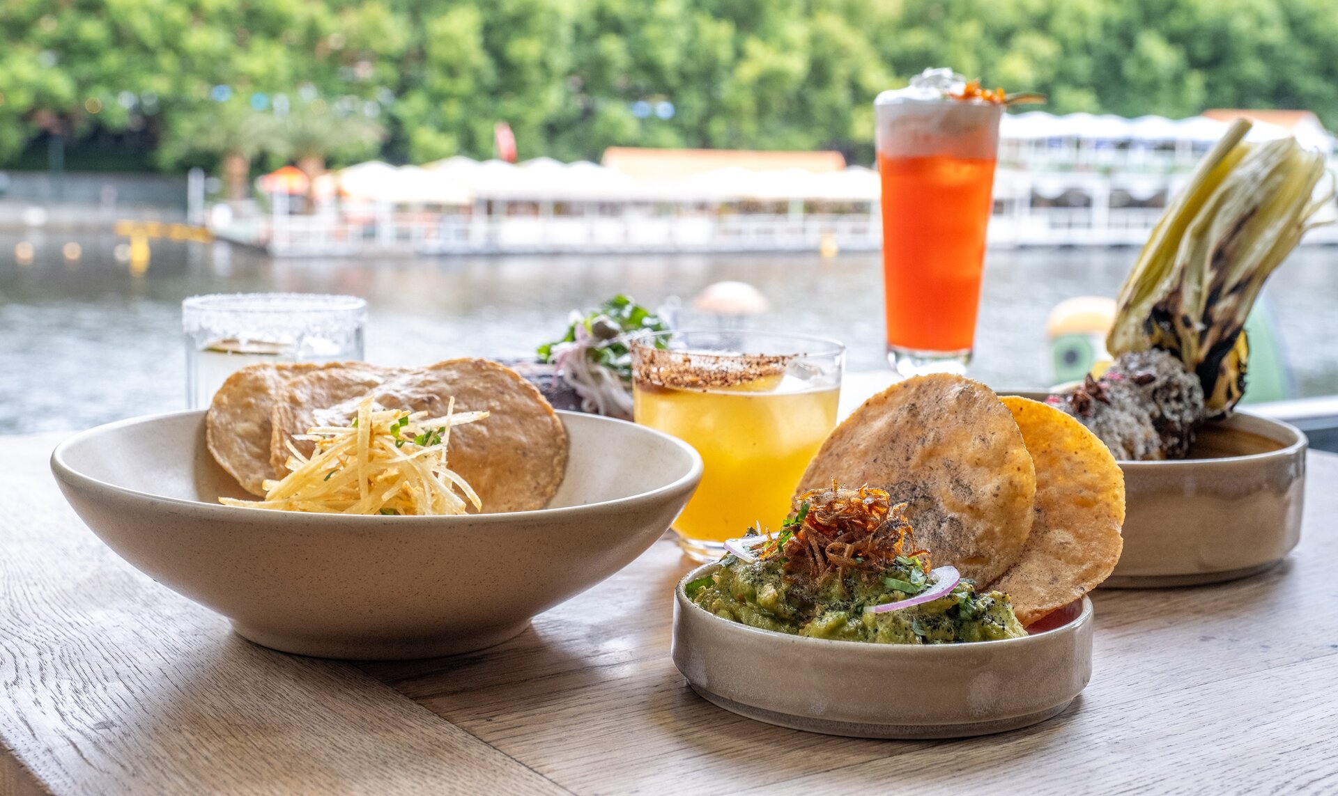 Plates of Mexican food including nachos, guacamole, corn and cocktails.