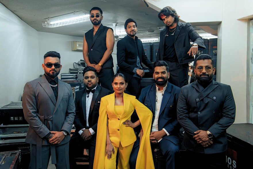 A group of eight people, including several Sri Lankan artists from the Naadha Gama – The Orchestral Edition, posing for a photo indoors.