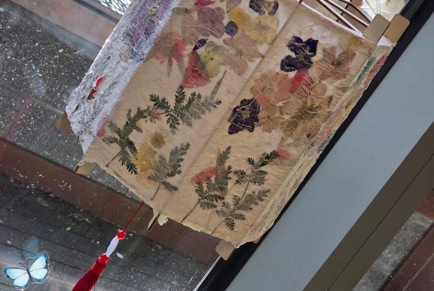 A decorated lampshade featuring homemade paper and pressed flowers. 