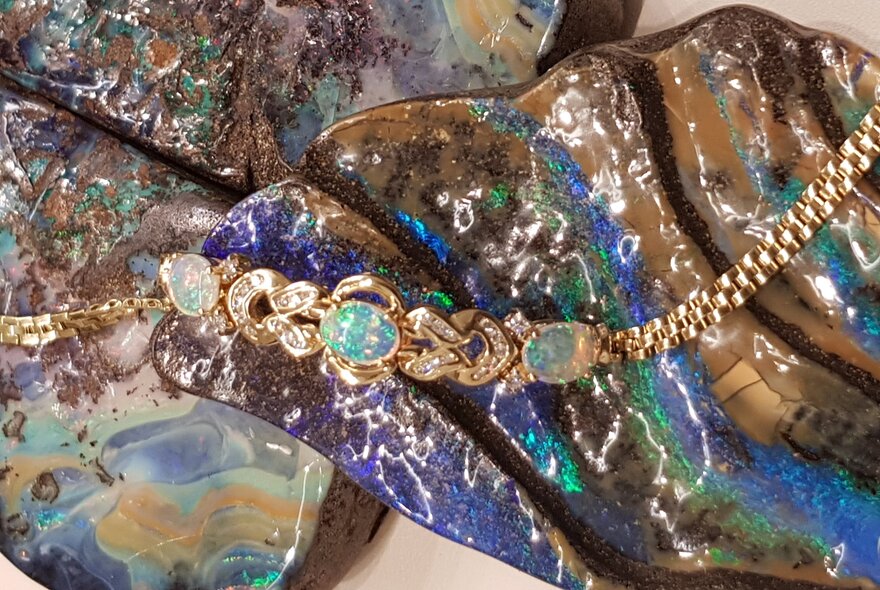 Opal and gold necklace draped over coloured stones.